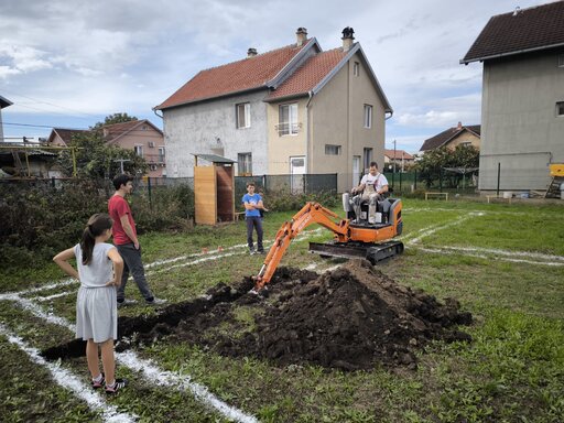 Ljudi pored bagera koji kopa zemlju